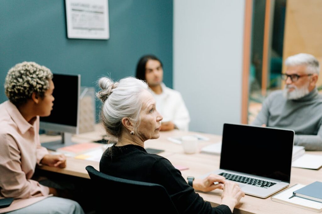 Free Woman in Black Sweater Sitting on Chair in Front of Macbook Pro Stock Photo